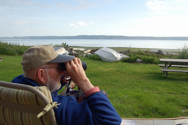 Using Binoculars To Check Out The Sights Of Saratoga Passage And Camano Island From Bells Beach In Langley On Whidbey Island