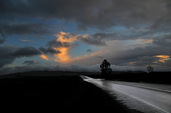 Mamalahoa Highway on Big Island of Hawaii with rain-covered road and sunset colors in clouds