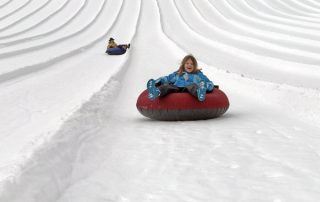 Inner tube riders on snow hill at Snoqualmie Pass Summit Tubing Center